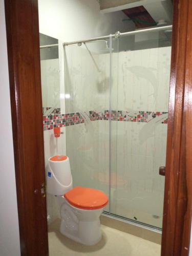 a bathroom with a shower with a toilet with a orange seat at hermoso apartamento en guaduas (apto 202) in Guaduas