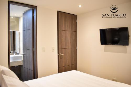 a bedroom with a bed and a tv on a wall at HOTEL SANTUARIO in Tunja