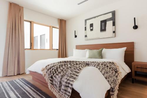 a bedroom with a large bed with white walls and windows at Sonder Lüm in Inglewood