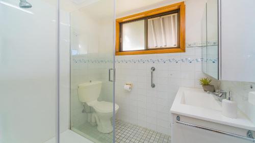 une salle de bain avec toilettes et douche en verre dans l'établissement Peninsula Court Unit 10, à Yamba