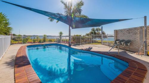a swimming pool in a yard with a palm tree at Peninsula Court Unit 9 - Absolute Waterfront Escape - Holiday Yamba in Yamba