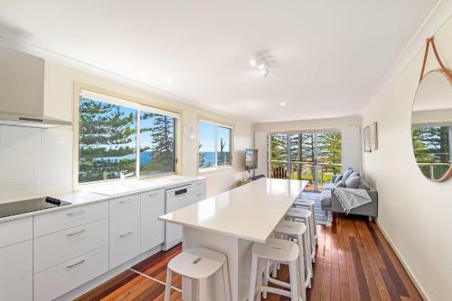 a kitchen with white cabinets and a large island with stools at Seaspray 1 in Yamba