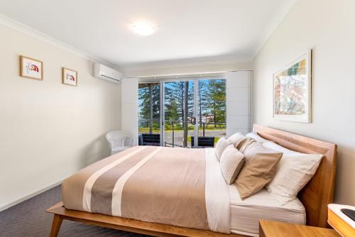 a bedroom with a large bed and a window at Seaspray 1 in Yamba