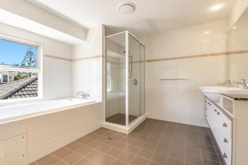a bathroom with a shower and a tub and a sink at Villa 63 - Resort Style Living - Holiday Yamba in Yamba