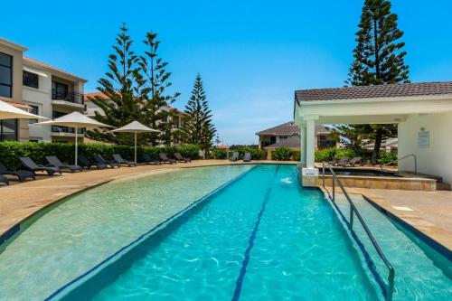 a swimming pool at a resort with chairs and umbrellas at Villa 63 - Resort Style Living - Holiday Yamba in Yamba