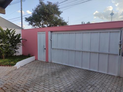 a garage with a pink and white building at Lindo quarto c/ banheiro privativo in Jaú