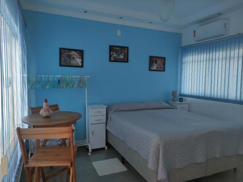 Dormitorio azul con cama y mesa en Lindo quarto c/ banheiro privativo, en Jaú
