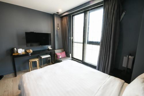 a bedroom with a white bed and a large window at Urban Island Hotel Jeju in Jeju