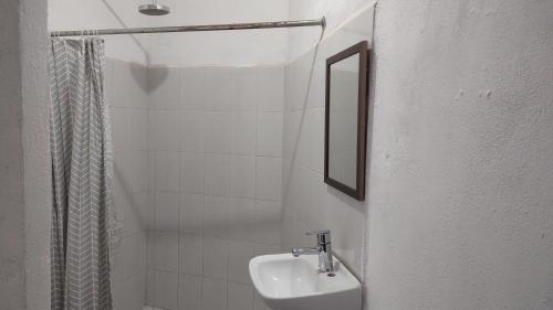 une salle de bain blanche avec un lavabo et un miroir dans l'établissement Casa maleni 2 en mismaloya, à Puerto Vallarta