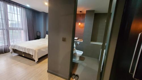 a bedroom with a bed and a bathroom with a toilet at Urban Island Hotel Jeju in Jeju