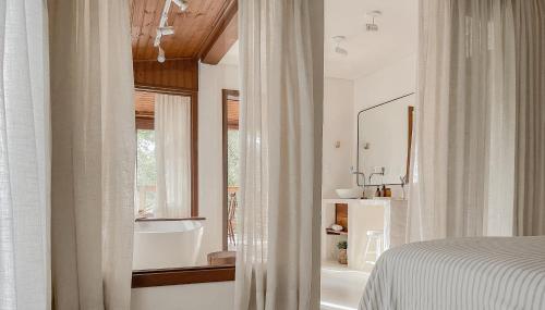 a bedroom with a bed and a bathroom with a tub at Aurora e Vale in Praia do Rosa