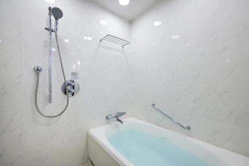 a white bathroom with a tub and a shower at The Royal Park Hotel Fukuoka in Fukuoka