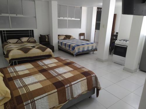 トルヒーリョにあるAmbigua Hospedajeのベッドルーム1室(ベッド2台付)、キッチンが備わります。