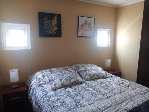 a bedroom with a bed and two windows at Departamento Amoblado a Pasos del Faro in La Serena