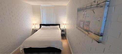 Un dormitorio pequeño con una cama con sábanas blancas. en Sky High on Arundel - central Fremantle apartment, en Fremantle
