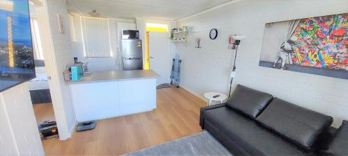 Una sala de estar con un sofá y una cocina. en Sky High on Arundel - central Fremantle apartment, en Fremantle