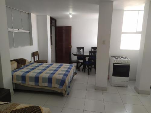 a room with a bed and a kitchen and a table at Ambigua Hospedaje in Trujillo