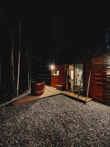 a person standing outside of a cabin at night at Container ABOBORA na natureza da Serra Gaúcha in Flores da Cunha
