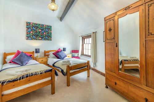 a bedroom with two twin beds and a dresser at Saddlers Cottage in Matlock