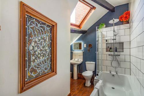 ein Badezimmer mit Badewanne und Toilette und einem Fenster in der Unterkunft Saddlers Cottage in Matlock