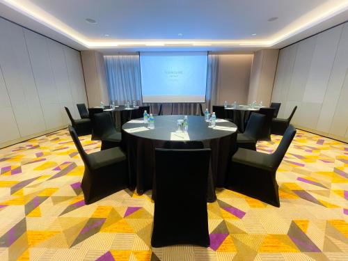 a conference room with tables and chairs and a screen at Mercure Kuala Lumpur Glenmarie in Shah Alam