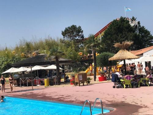 un complexe avec une piscine avec des personnes et des parasols dans l'établissement La Perle Marine - Sud Nantes Atlantic toboggan, à Saint-Hilaire-de-Riez