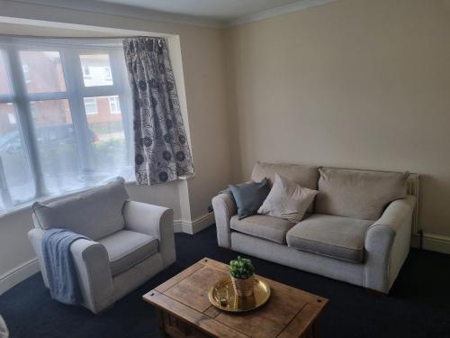 a living room with two couches and a coffee table at Lovely residential home 2 bed apartments in Goodmayes