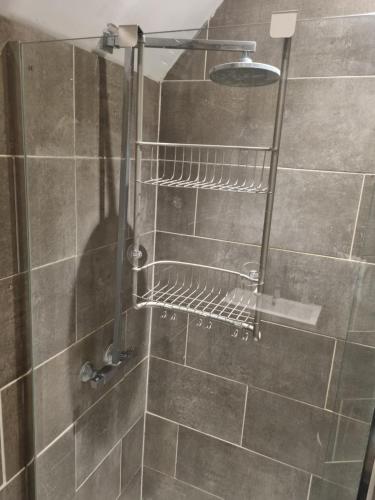 a shower with a metal rack in a bathroom at Lovely residential home 2 bed apartments in Goodmayes