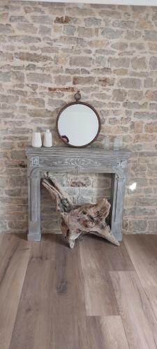 - une table avec un miroir à côté d'un mur de briques dans l'établissement Gîte chez Marianne- la halte Jurassienne, à Montmorot
