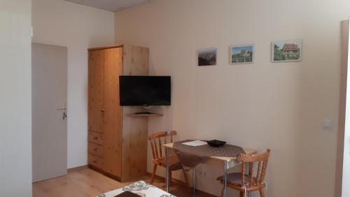a room with a table and a television and a table and chairs at Pension Lehmann in Radebeul