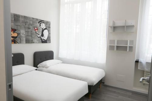 2 łóżka w pokoju z białymi ścianami i oknem w obiekcie LA CORTE LUXURY APARTMENT w Mediolanie