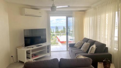 a living room with a couch and a flat screen tv at Coastal Apt At Kings Beach, Stunning View in Caloundra