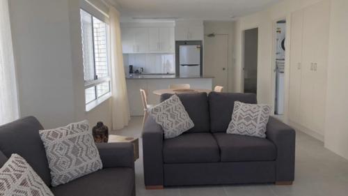 a living room with a couch and a kitchen at Coastal Apt At Kings Beach, Stunning View in Caloundra