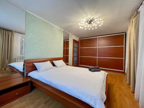 a bedroom with a large bed and a chandelier at Букетова 65 2-комн квартира с гостиничным сервисом с белым постельным in Petropavlovsk