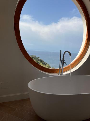 un bagno con una grande finestra rotonda e una vasca da bagno di Agapanto Luxury Accommodation a Ischia