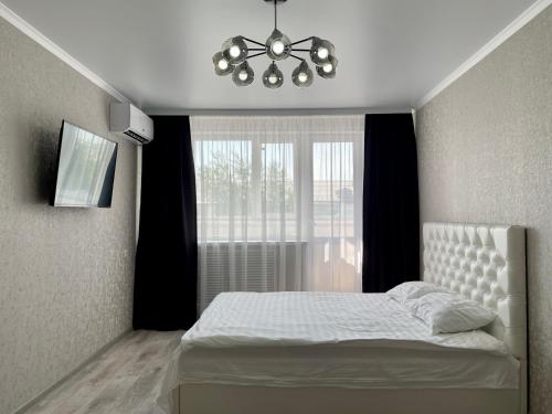 1 dormitorio con cama blanca y ventana en Стильная квартира с кондиционером, en Petropavlovsk