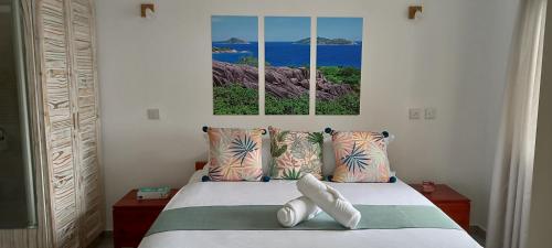 um quarto com uma cama com duas fotografias na parede em Harmony Self-Catering Apartments em Beau Vallon