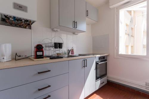 une cuisine avec des armoires blanches et une fenêtre dans l'établissement Lumineux 70m cosy à proximité de la plage, à Arcachon