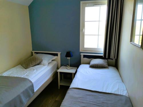 two beds in a small room with a window at Les Roseaux - Piscine chauffee in Talmont-Saint-Hilaire