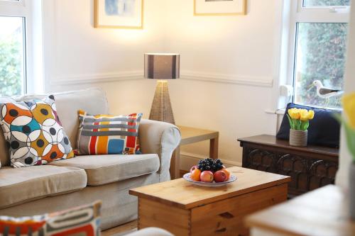 a living room with a couch and a table with a bowl of fruit at Tamarisk, Port Isaac Bay Holidays in Port Isaac