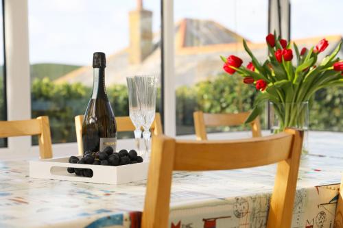 a table with a bottle of wine and flowers on it at Tamarisk, Port Isaac Bay Holidays in Port Isaac