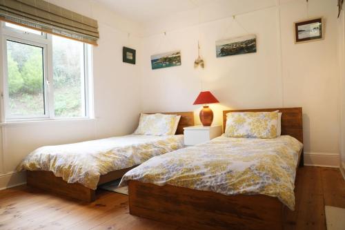 a bedroom with two beds and a window at Tamarisk, Port Isaac Bay Holidays in Port Isaac