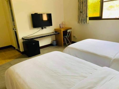 a hotel room with two beds and a television at Fuzhongju Homestay in Jincheng