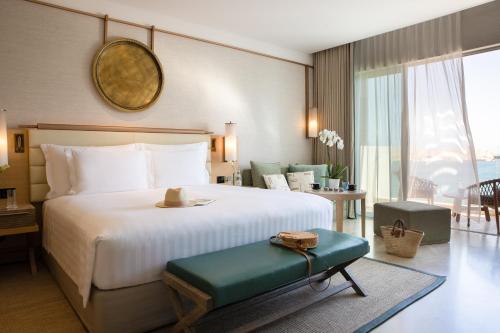 - une chambre avec un grand lit et une grande fenêtre dans l'établissement Jumeirah Muscat Bay, à Mascate