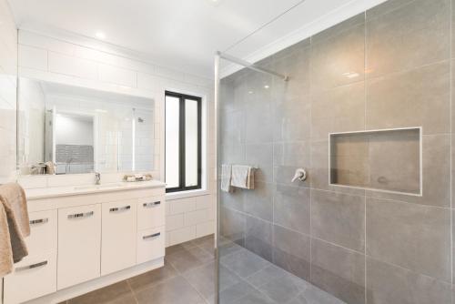 ein Bad mit einer Dusche, einem Waschbecken und einem Spiegel in der Unterkunft Allara Motor Lodge in Bendigo