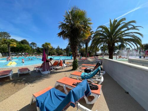 - une piscine avec des chaises longues et un groupe de personnes dans l'établissement Mobil home XXL - Bord LAC - CAMPING Les Viviers - Lège cap ferret, à Lège-Cap-Ferret