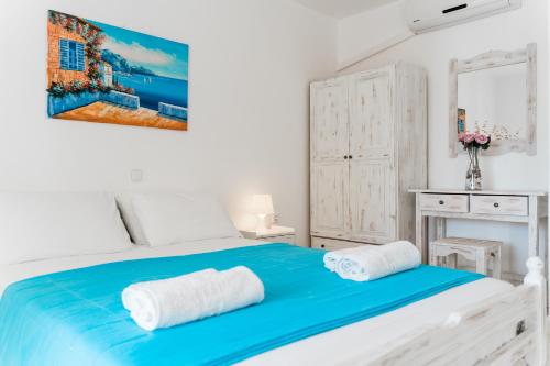 a white bedroom with a blue bed with two towels at Villa Kallithea in Parga