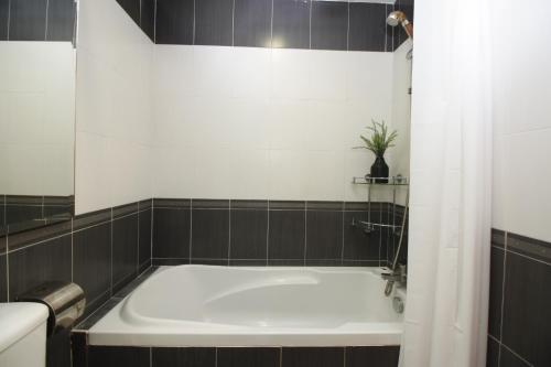 a bath tub in a bathroom with black tiles at UBN by Plush in Kuala Lumpur