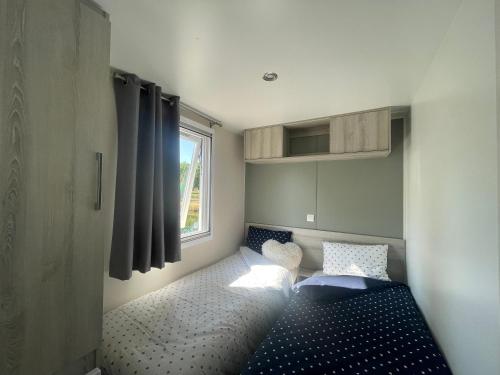 Una pequeña habitación con una cama y una ventana. en Mobil home XXL - Bord LAC - CAMPING Les Viviers - Lège cap ferret, en Lège-Cap-Ferret