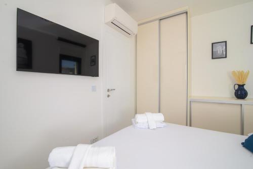 a bedroom with a white bed with a tv on the wall at Ero on the beach in Trogir